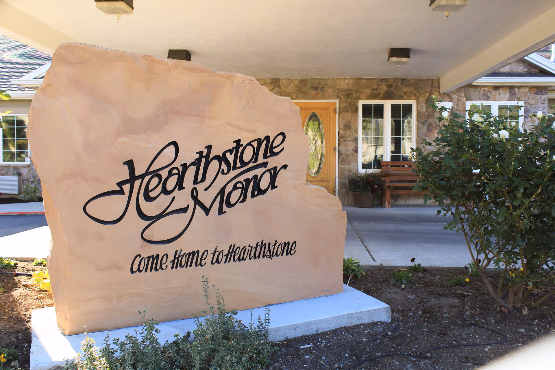 Exterior view of Hearthstone Manor with a large stone sign and front entrance.