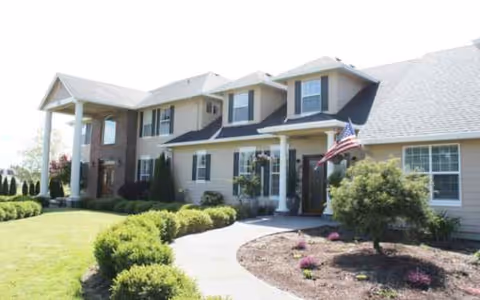 Front view of a senior living facility with a beige exterior, entrance, and landscaped walkway.