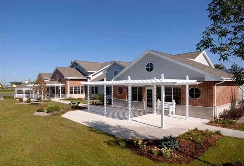 Exterior view of Rennes Health and Rehab Center De Pere with brick walls and white pergolas.