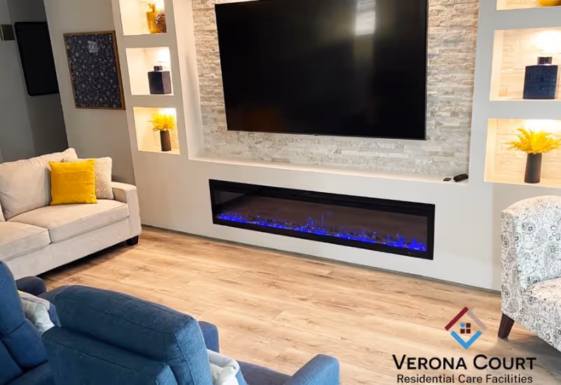 Modern living room with wall-mounted TV, electric fireplace, built-in shelves, and cozy seating.