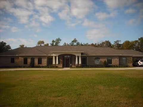 Single-story brick senior living facility exterior with a central entrance and lawn.