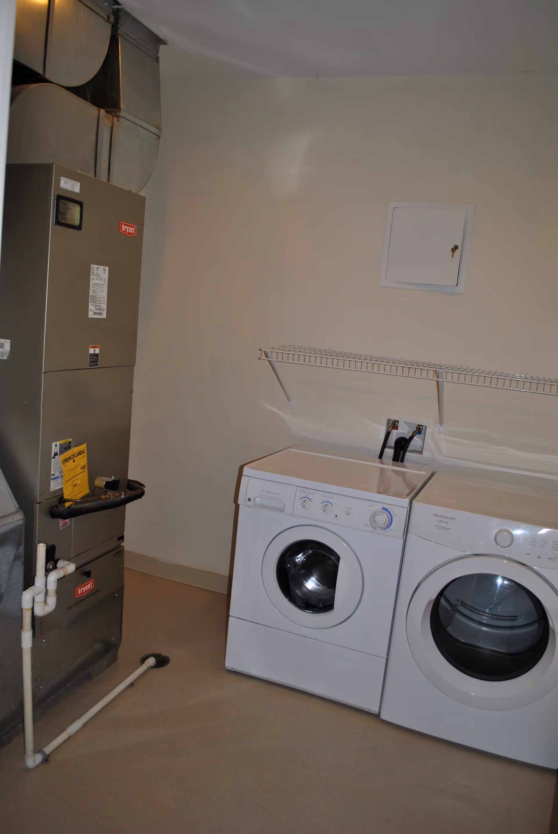 A laundry/utility room with a washer and dryer side by side and an HVAC unit to the left.
