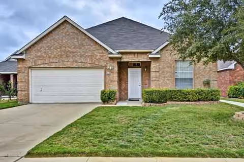 A brick residential building with a two-car garage and front lawn.