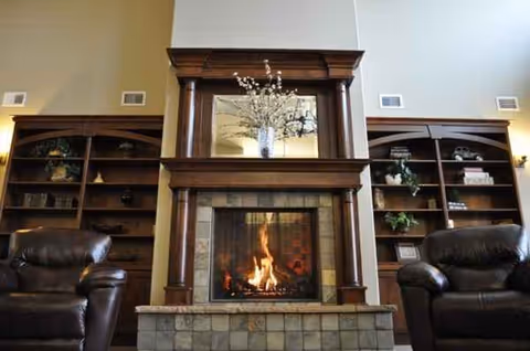 Cozy living room with a wood mantle fireplace, built-in shelves, and dark leather chairs.
