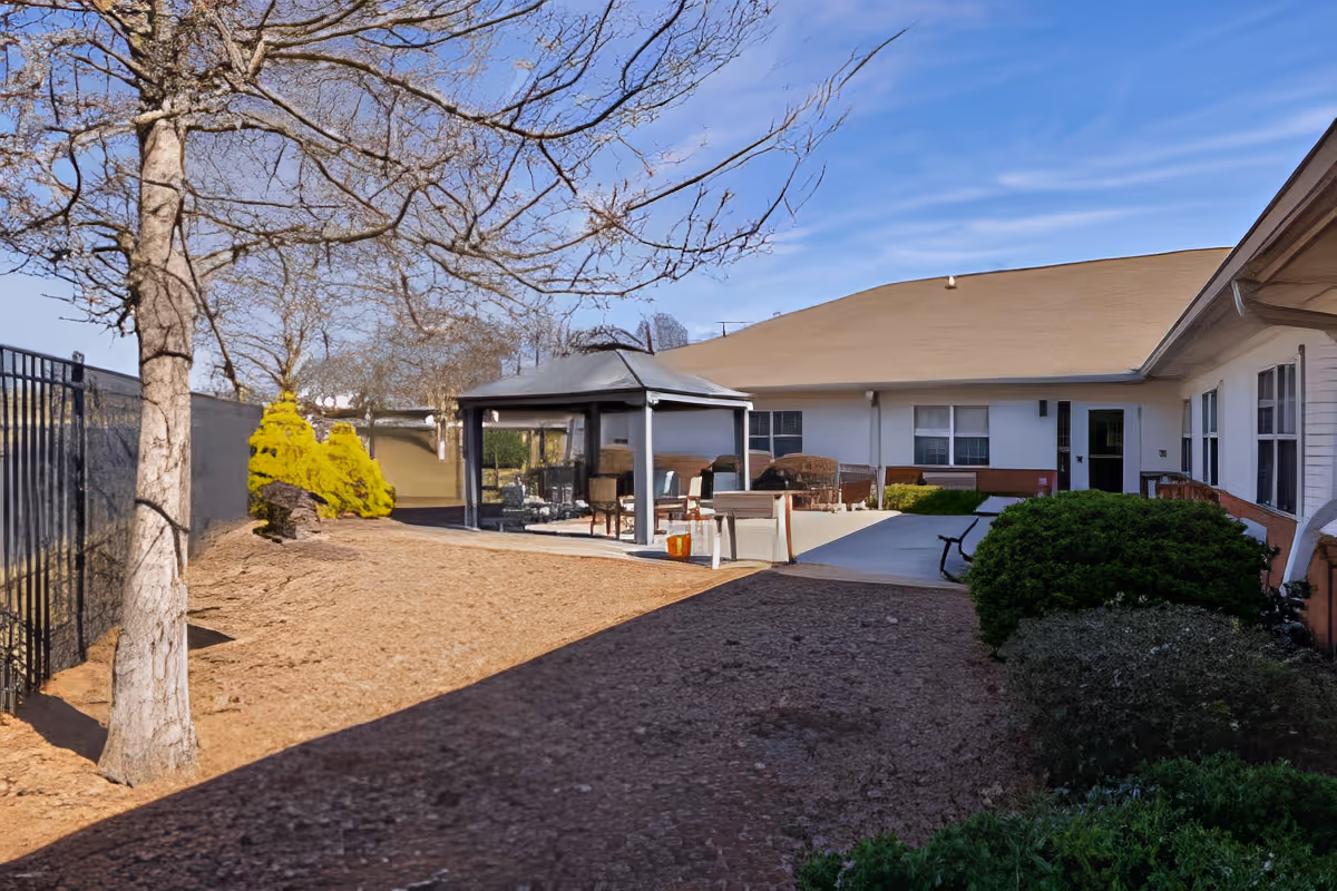 Courtyard patio area with a gazebo, outdoor seating, trees and a surrounding single-story building.