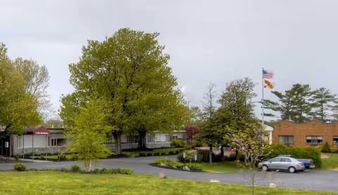 Exterior view of Complete Care at Hagerstown with trees, flag, and parked cars.