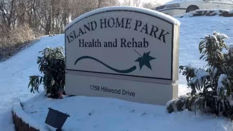 Snow-covered landscape featuring Island Home Park Health and Rehab sign.