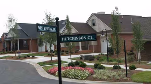Exterior view of a senior living campus with landscaped frontage and street signs.