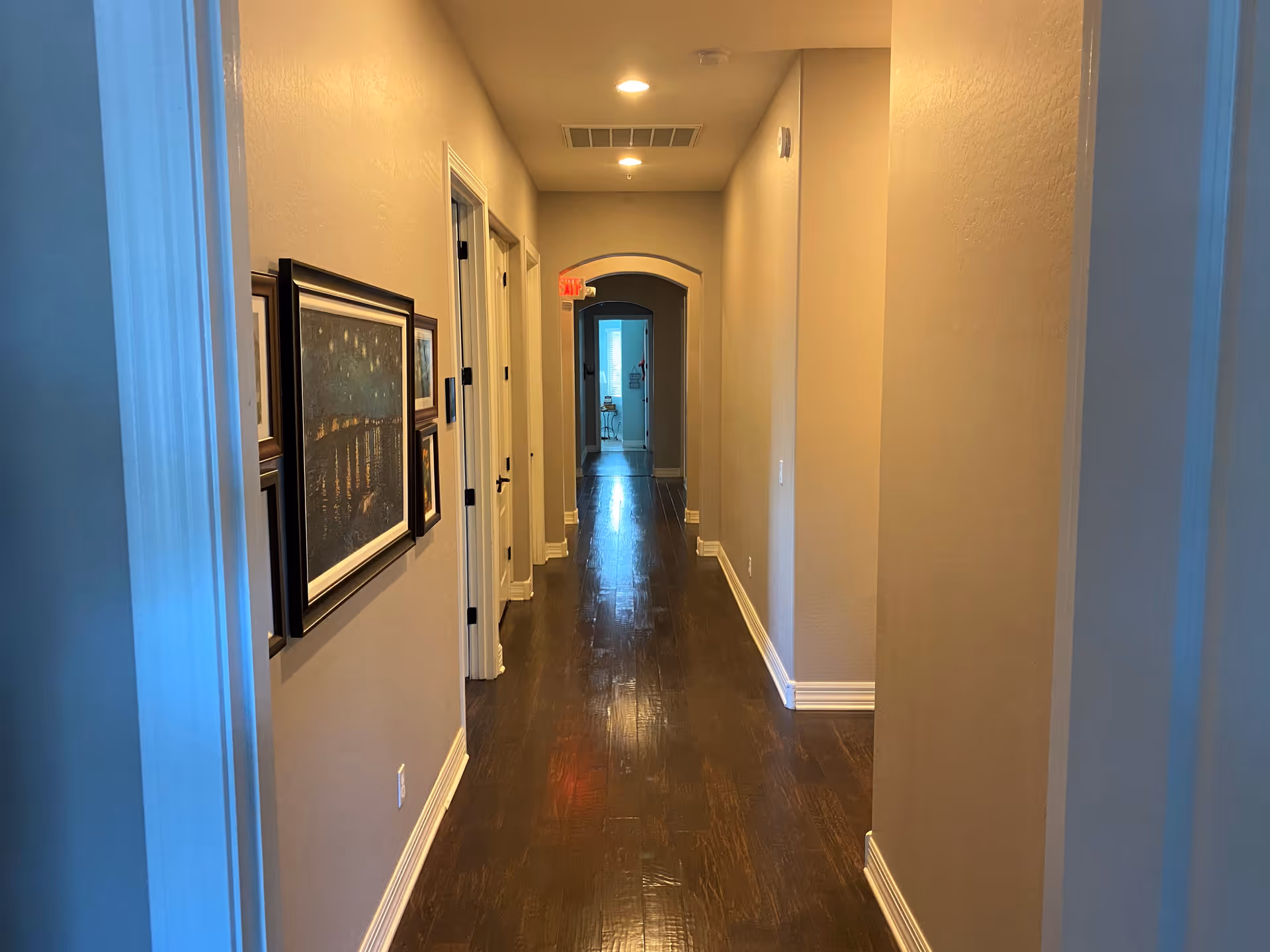 A long hallway in a senior living facility with framed art along walls.