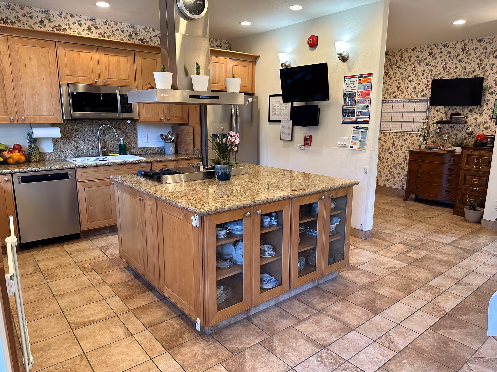 Kitchen with a large granite-topped island, wooden cabinets, stainless steel appliances and tiled floor.