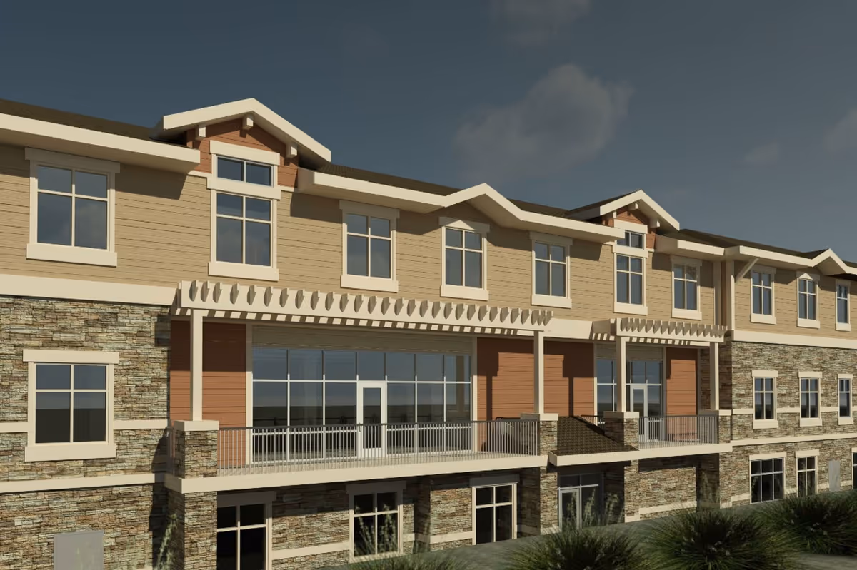 Exterior view of a multi-story senior living facility building with stone and beige siding, multiple windows, and balconies under a partly cloudy sky.