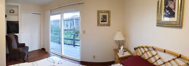 Bedroom with a bed and nightstand, armchair and closet, and sliding glass door opening to an outdoor deck.