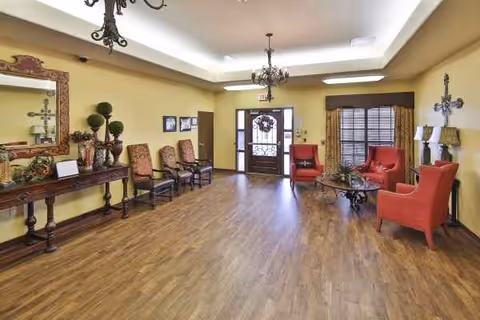 Lobby-style interior with yellow walls, wooden floor, and red armchairs near the entrance.