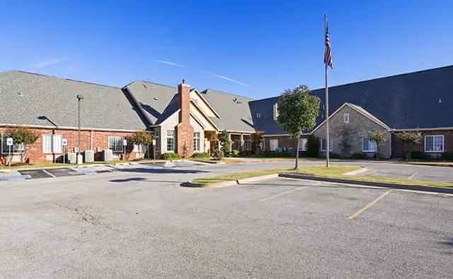 Exterior view of Legend Memory Care at Rivendell with parking lot and flagpole.