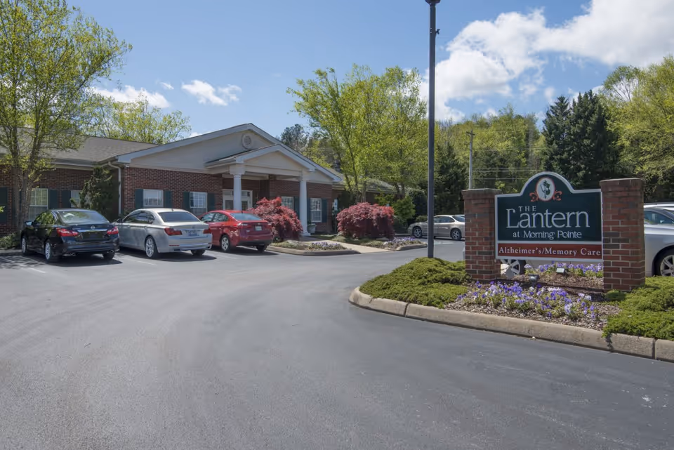 Exterior view of The Lantern at Morning Pointe Alzheimer's Center with parked cars and sign.