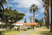 Exterior front of Villa Health Care Center showing a covered entrance, palm trees, lawn, and a walkway.