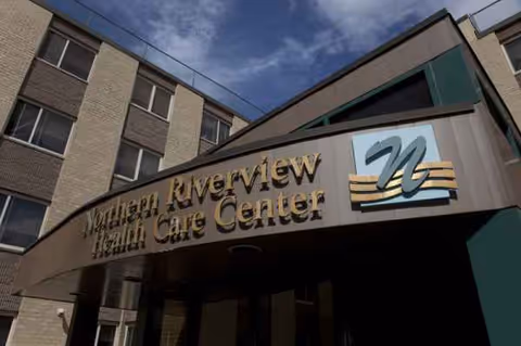 Facade of a senior care center with curved entrance and Northern Riverview Health Care Center sign.