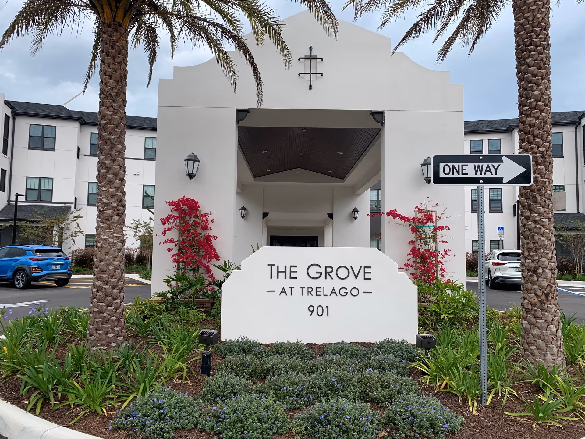 Entrance and sign reading "The Grove at Trelago 901" in front of a three-story building with palm trees and landscaping.