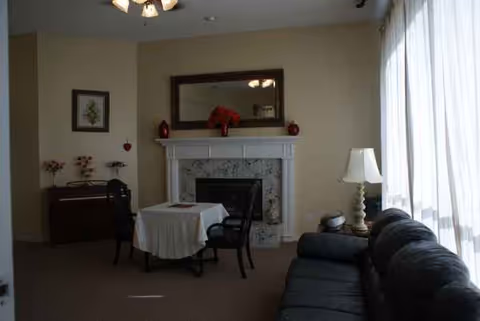 Cozy living area featuring a fireplace, sofa, small dining table, and large windows.