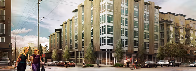 Street view of a modern multi-story residential building with large windows and balconies. People are walking on the sidewalks and cars are parked along the street in an urban setting.