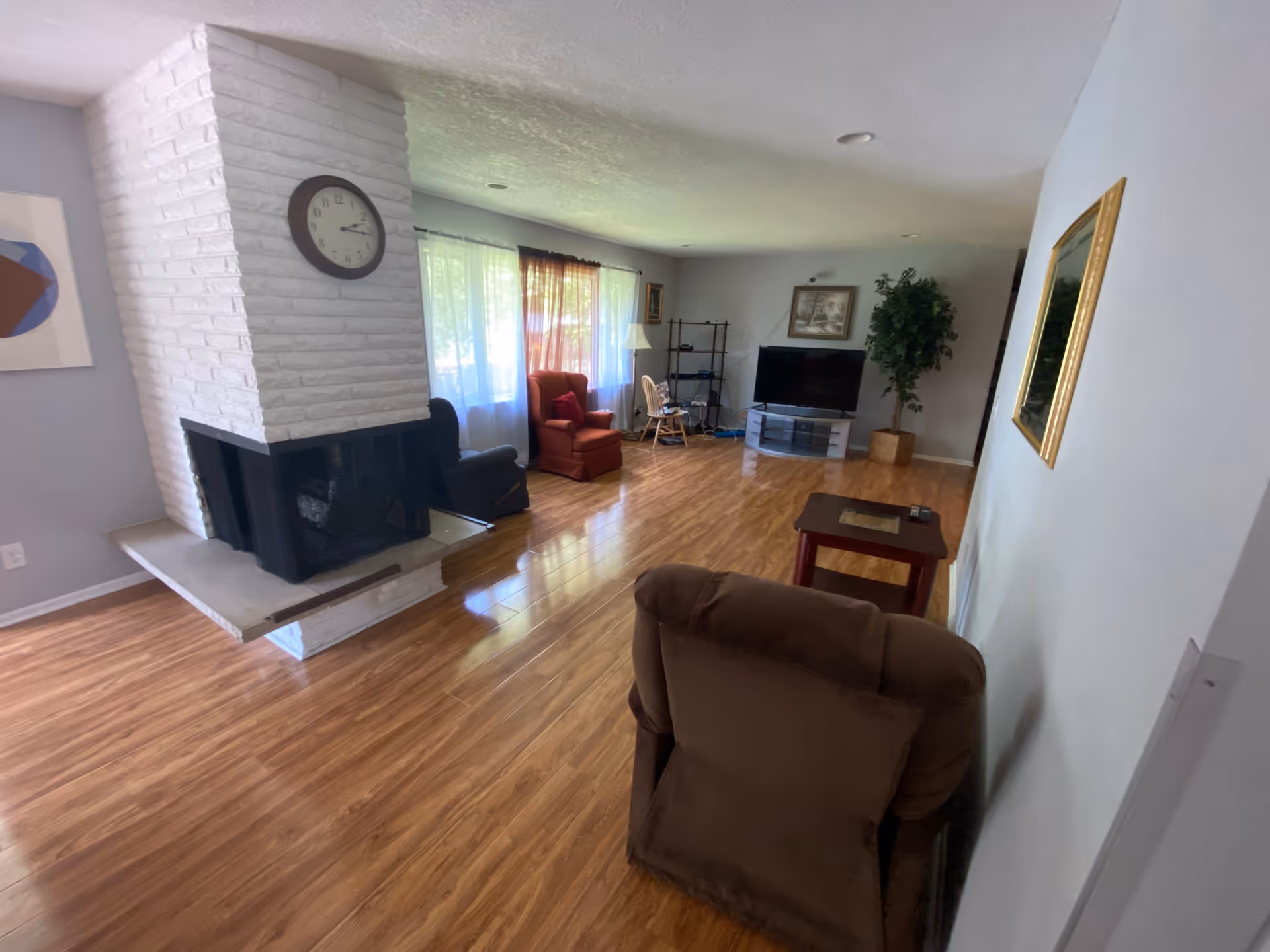 Spacious living room with a white brick fireplace, seating area, and a TV.
