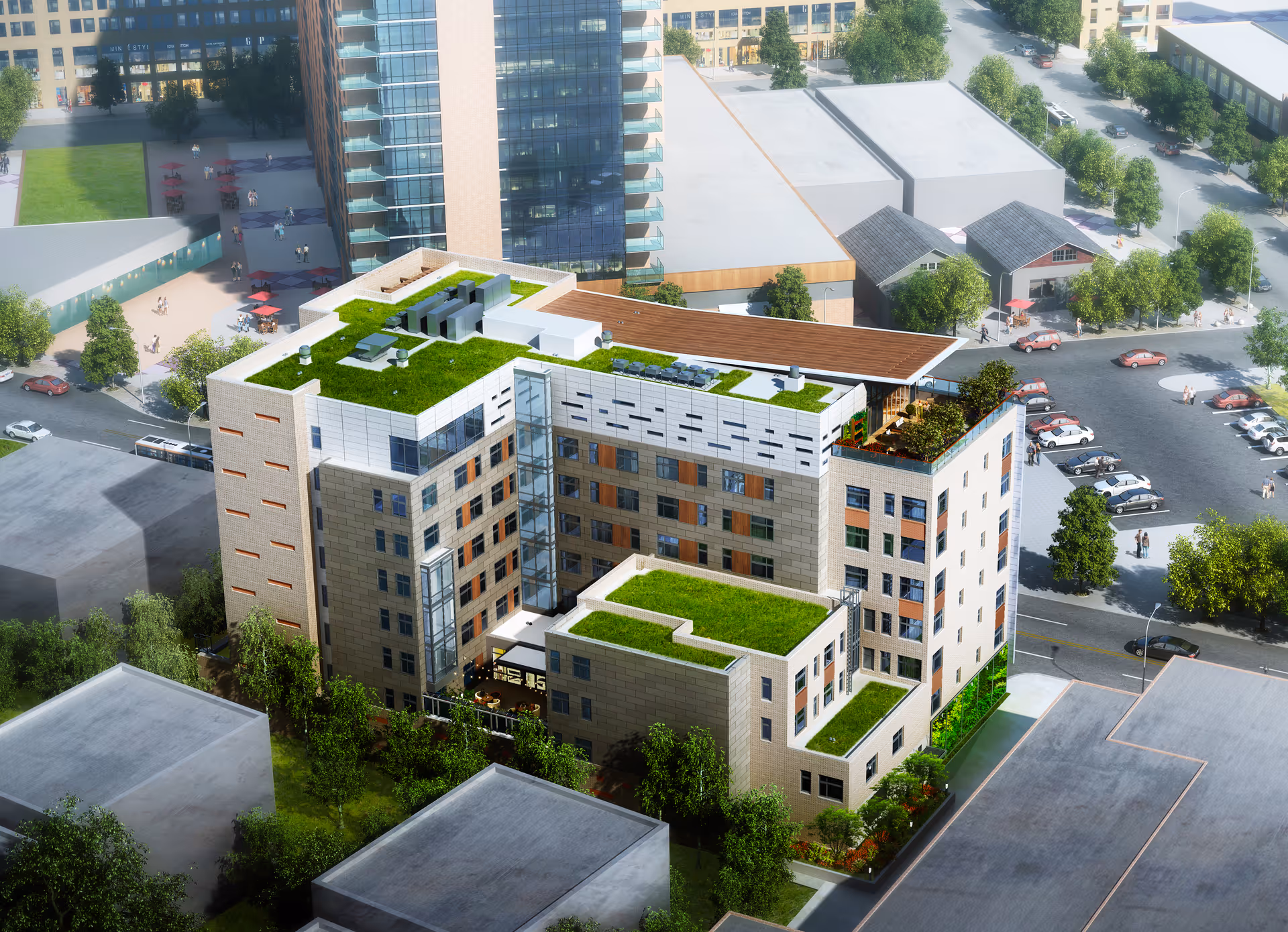 Aerial view of a multi-story residential building with green rooftop gardens surrounded by streets, parking lots, and nearby buildings.
