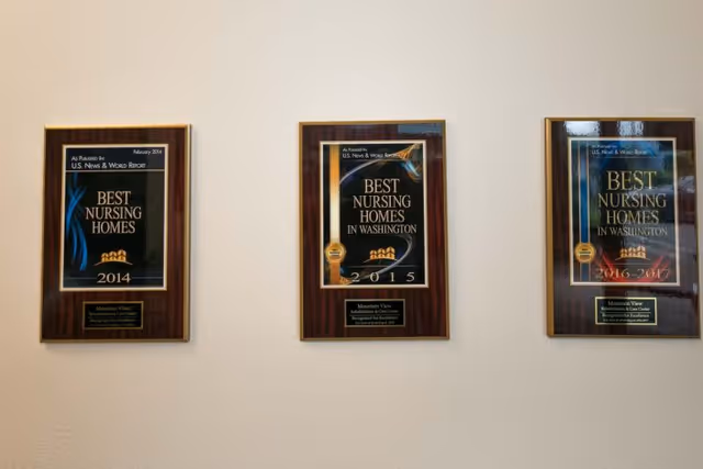 Three framed plaques hanging on a beige wall, each recognizing Mountain View Rehabilitation and Care Center as one of the best nursing homes in Washington for the years 2014, 2015, and 2016-2017.