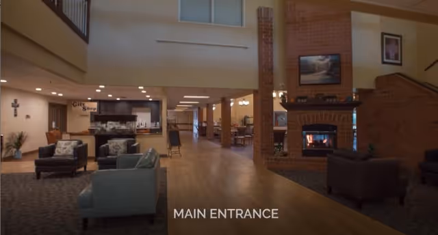 Spacious main entrance lobby with seating, a fireplace, and a view toward a gift shop and dining area.