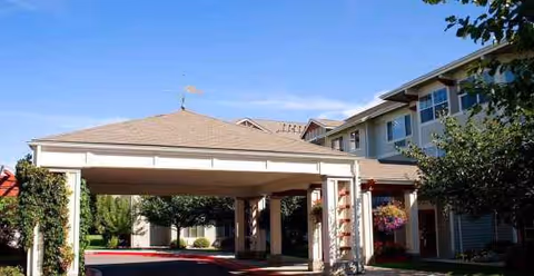 Exterior view of Holiday Grizzly Peak senior living facility with a covered entrance and landscaping.