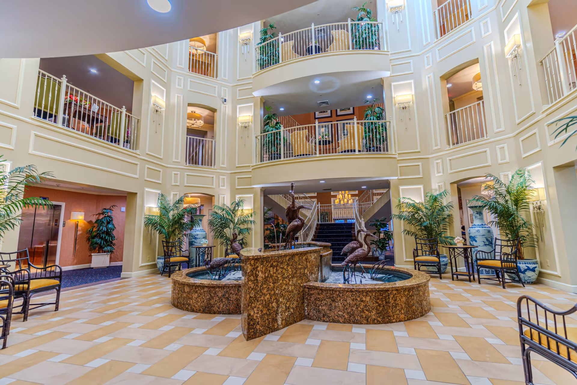 Spacious multi-story atrium with a central fountain, seating areas, potted plants, and surrounding balconies.