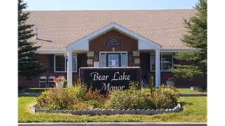 Front view of a brick building with a landscaped sign that reads "Bear Lake Manor".