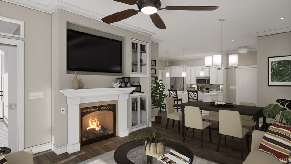 A modern open-concept living and dining area with a lit fireplace beneath a mounted flat-screen TV. The room features a ceiling fan, a dining table with six chairs, a round coffee table with a plant, and a kitchen with white cabinetry and stainless steel appliances in the background. There are decorative plants and framed artwork on the walls.