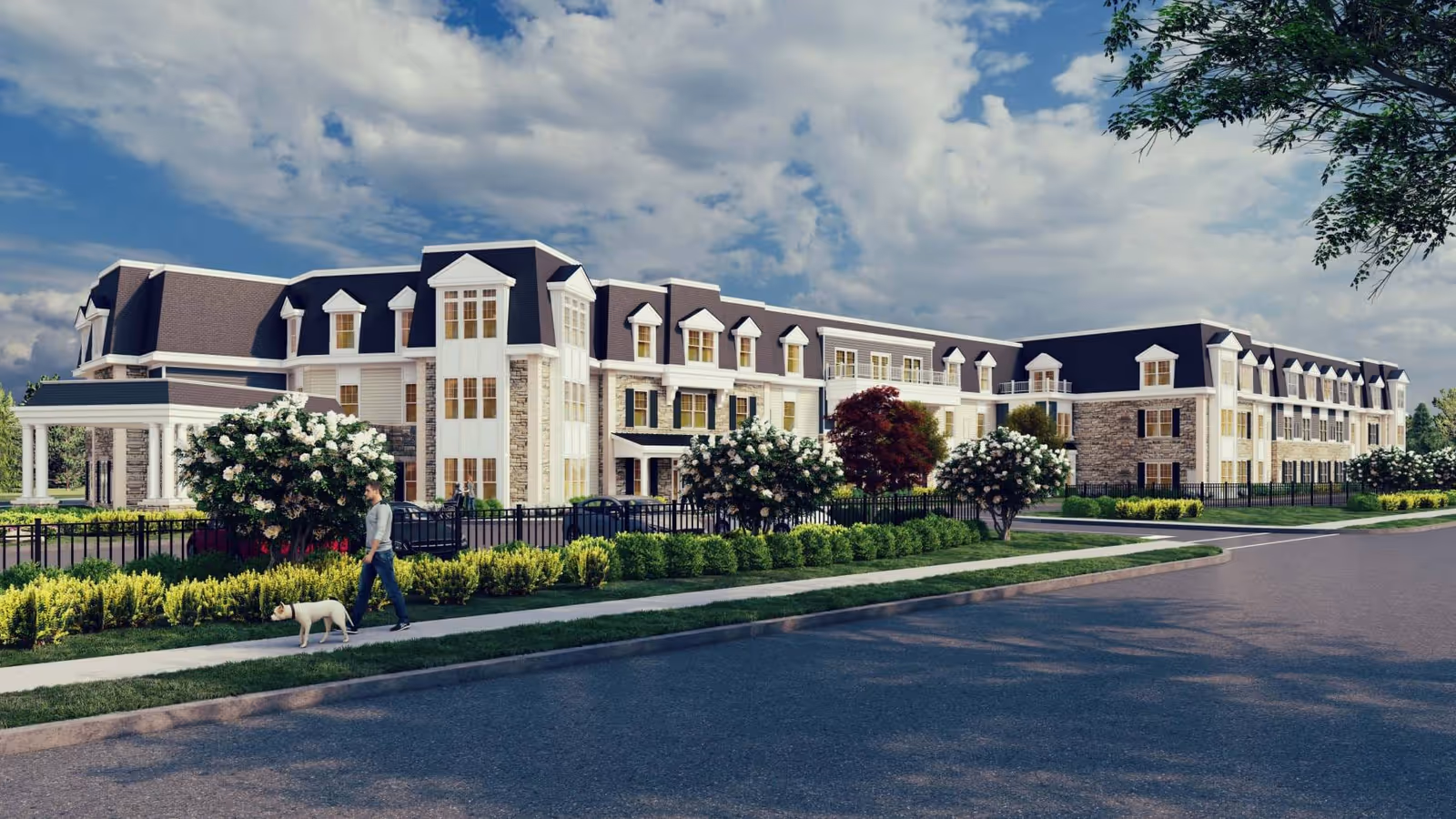 Front exterior of a large multi-story senior living building with landscaped grounds and a person walking a dog along the sidewalk.