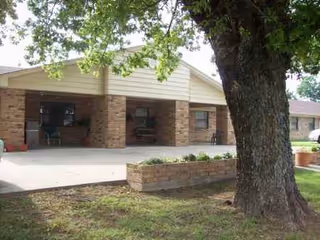 Elmwood Manor Nursing Home exterior with brick facade, covered entrance, and a large tree.
