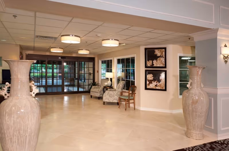 Entry lobby with large decorative vases, seating area, artwork, and glass entrance doors.