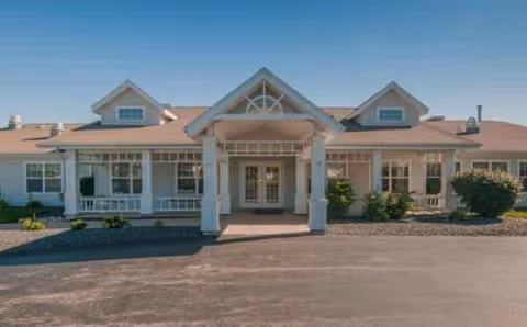 Front view of a single-story senior living facility with a covered entrance and columns.