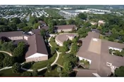 Aerial view of a senior living campus with brown-roofed buildings, trees, and curved walkways.