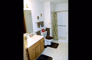Bathroom featuring sink, toilet, and shower with curtain in a retirement community unit.