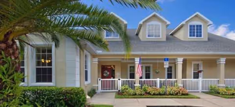 Front exterior of a Brookdale senior living building with a covered porch and palm tree.