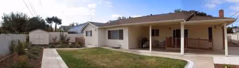 Single-story residential facility with a covered front porch, lawn, and walkway.