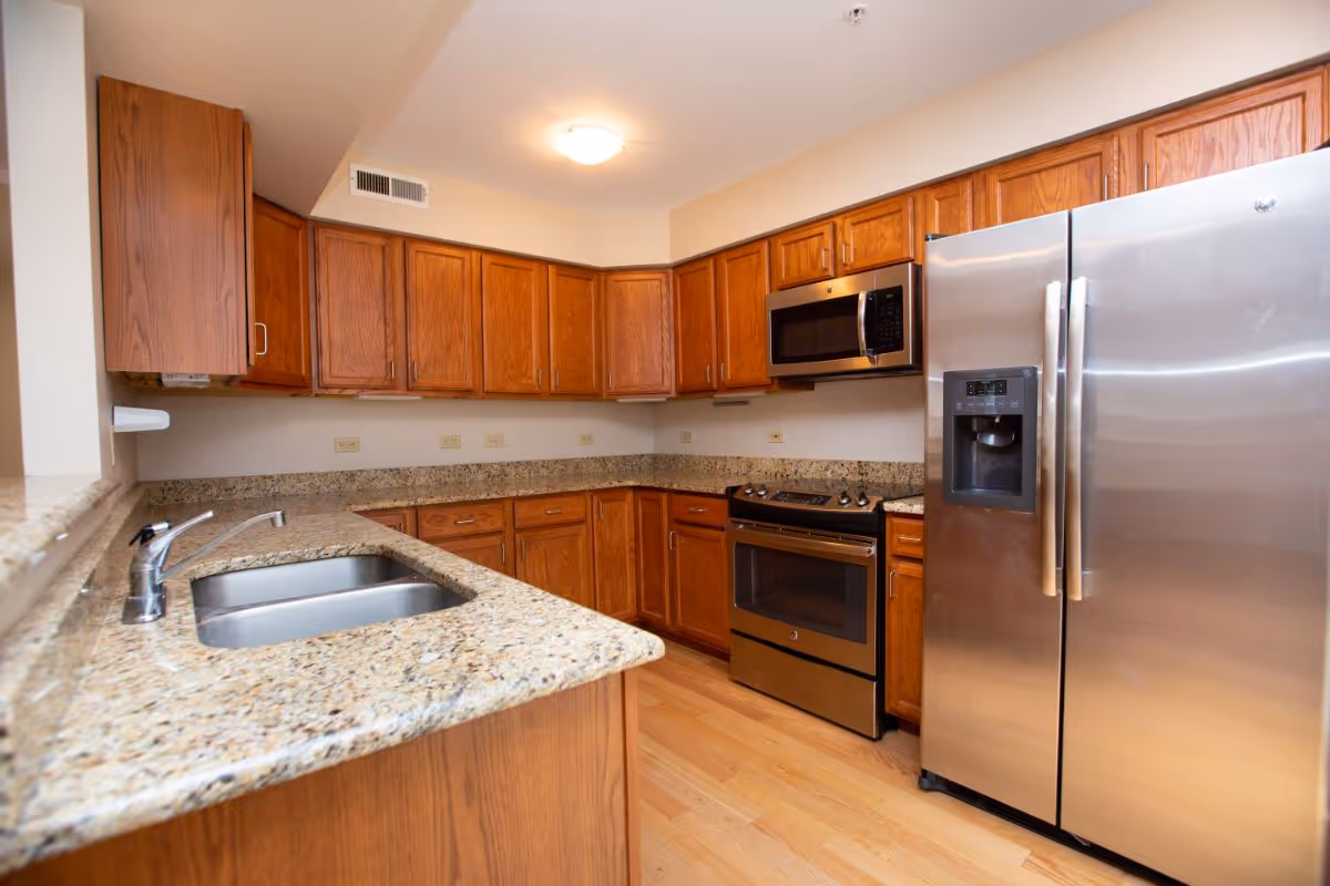 Modern kitchen with granite countertops, wood cabinets, and stainless-steel appliances.