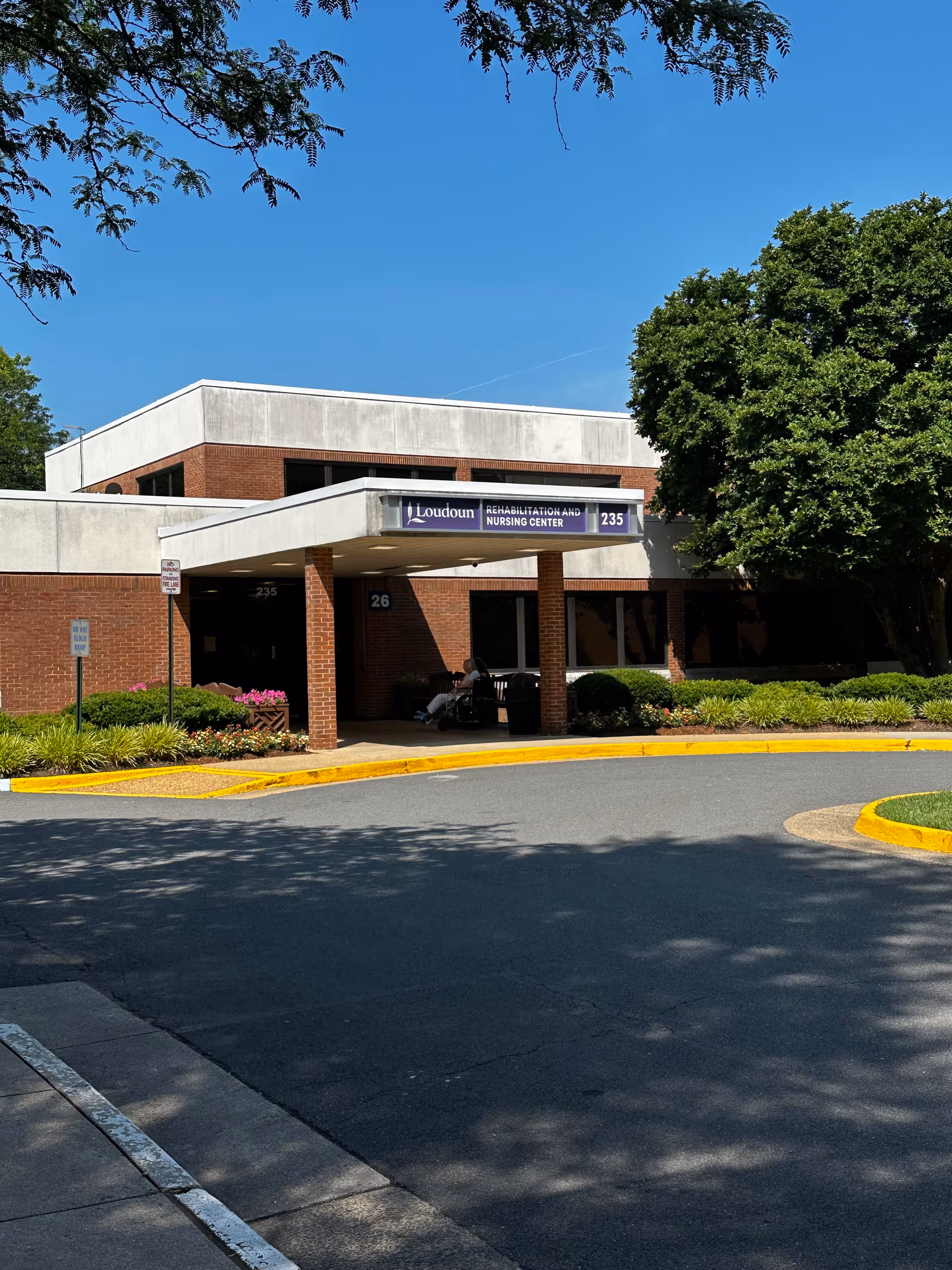 Front entrance of Loudoun Rehabilitation and Nursing Center with a covered drop-off, visible signage, and landscaped grounds.