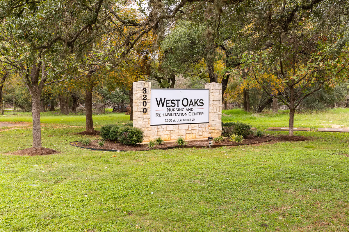 Stone sign for West Oaks Nursing and Rehabilitation Center at 3200 W. Slaughter Ln, surrounded by green grass, trees, and landscaping.