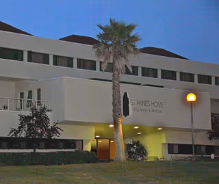 Exterior view of St. Anne's Home for the Aged with a palm tree in front.