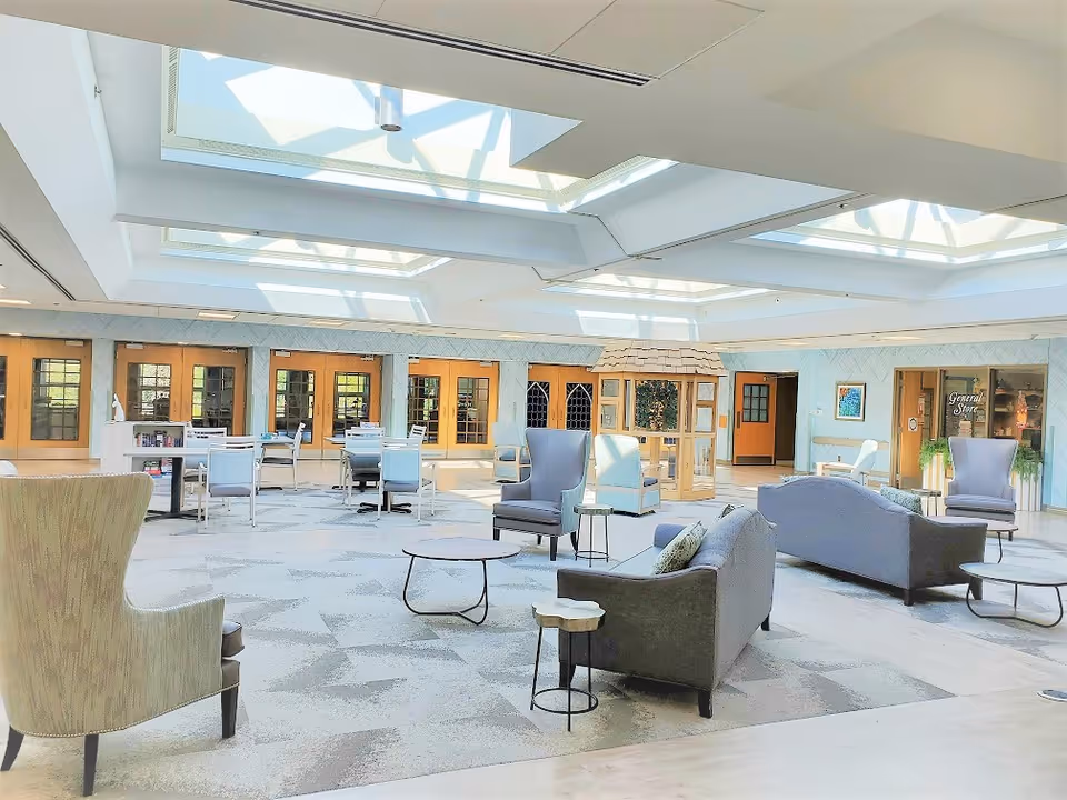 Spacious sunlit communal lounge with skylights, sofas, armchairs, and tables.