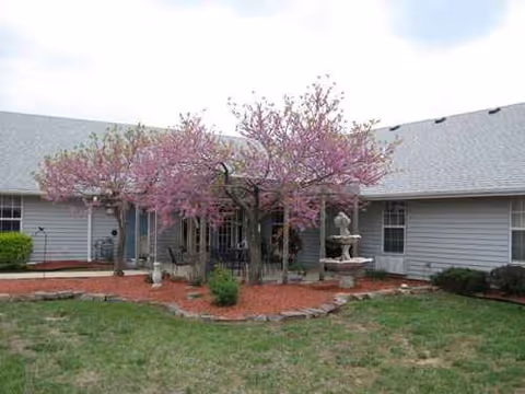 Front view of a single-story senior living facility with pink flowering trees.