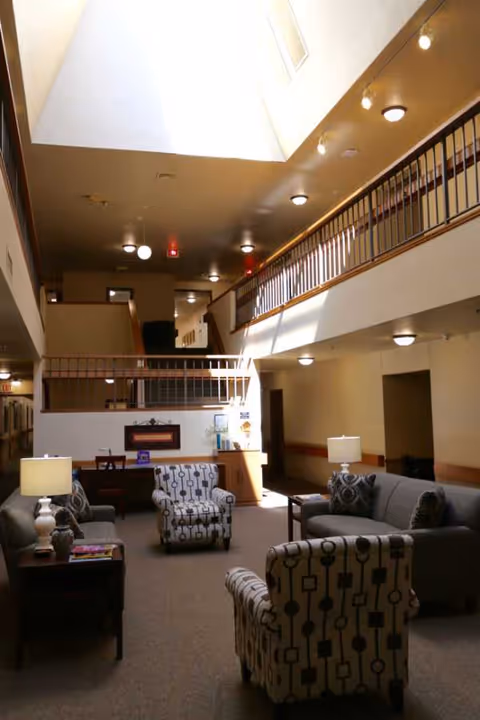 Spacious two-story lounge with sofas, chairs, lamps, and a second-floor balcony.