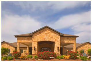 Front view of a stone-brick senior care facility entrance with landscaped grounds.