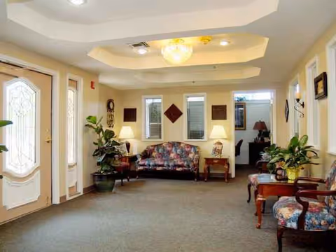 Lobby area of a senior living facility with sofas, lamps, and plants.