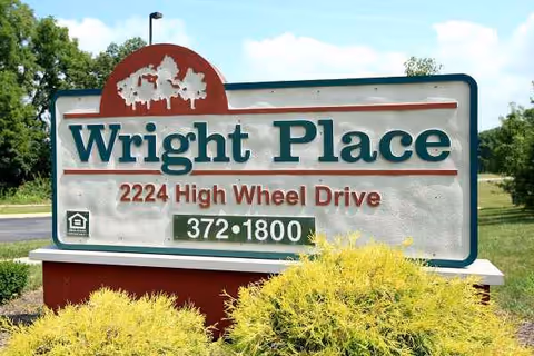 A Wright Place entrance sign with address and phone number, surrounded by landscaping.